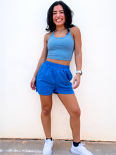 Load image into Gallery viewer, Young lady modeling comfortable Blue Sweatshorts in a lightweight material.