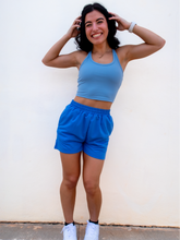 Load image into Gallery viewer, Young lady modeling comfortable Blue Sweatshorts in a lightweight material.