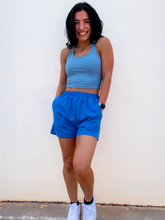 Load image into Gallery viewer, Young lady modeling comfortable Blue Sweatshorts in a lightweight material.