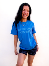 Load image into Gallery viewer, Blue graphic t-shirt with a whimsical "happy go lucky type vibe" design.
