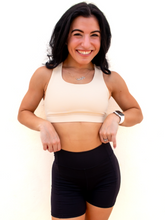 Load image into Gallery viewer, Young lady modeling a cream yellow colored sports bra with medium to high support and a unique racerback cut.