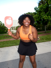 Load image into Gallery viewer, Orange colored sports bra with medium to high support and a unique racerback cut