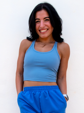 Load image into Gallery viewer, Young lady modeling a sky blue cropped racerback spandex tank with a built-in sports bra.
