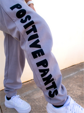Load image into Gallery viewer, Peachy Pia Positive Pants joggers. Grey lightweight jogger sweatpants with positive pants design down the front of the right leg and smiley face design on the back pocket. Joggers provide an elastic waist and cuffed ankles.