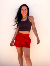 Load image into Gallery viewer, Young lady modeling comfortable red Sweatshorts in a lightweight material.