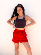 Load image into Gallery viewer, Young lady modeling comfortable red Sweatshorts in a lightweight material.