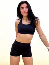 Load image into Gallery viewer, Young lady modeling Peachy Pia Peachy Shorts. Peachy Shorts are high-waisted in color black with a 75% nylon, 25% spandex blend. Extra stretchy fabric provides extra comfort while still providing a more fitted appearance.