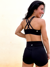 Load image into Gallery viewer, Young lady modeling Peachy Pia Peachy Shorts. Peachy Shorts are high-waisted in color black with a 75% nylon, 25% spandex blend. Extra stretchy fabric provides extra comfort while still providing a more fitted appearance.
