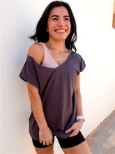 Load image into Gallery viewer, Young lady modeling a ribbed, beige sports bra that has medium/high support with a v neck front and scoop neck back.