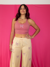Load image into Gallery viewer, Pink cropped tank top with a built-in sports bra and bow design on the front paired with tan sweatpants with pink bow pattern