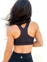 Load image into Gallery viewer, Lady modeling unique style black racerback sports bra.