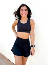 Load image into Gallery viewer, Lady modeling unique style black racerback sports bra.