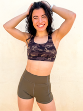 Load image into Gallery viewer, Young lady modeling Peachy Pia Peachy Shorts. Peachy Shorts are high-waisted in color olive green with a 75% nylon, 25% spandex blend. Extra stretchy fabric provides extra comfort while still providing a more fitted appearance.