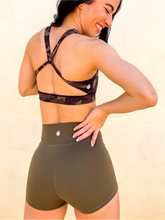 Load image into Gallery viewer, Young lady modeling Peachy Pia Peachy Shorts. Peachy Shorts are high-waisted in color olive green with a 75% nylon, 25% spandex blend. Extra stretchy fabric provides extra comfort while still providing a more fitted appearance.