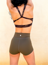 Load image into Gallery viewer, Young lady modeling Peachy Pia Peachy Shorts. Peachy Shorts are high-waisted in color olive green with a 75% nylon, 25% spandex blend. Extra stretchy fabric provides extra comfort while still providing a more fitted appearance.