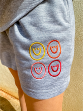 Load image into Gallery viewer, Grey, lightweight sweatshorts with multicolored smiley faces embroidered.