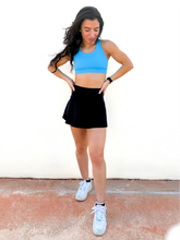 Load image into Gallery viewer, Lady modeling black tennis skort with built in side pocket.