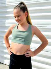 Load image into Gallery viewer, Young girl modeling muted green strappy sports bra.