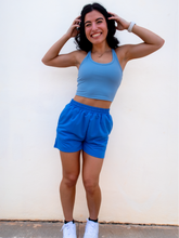 Load image into Gallery viewer, Young lady modeling comfortable Blue Sweatshorts in a lightweight material.
