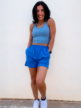 Load image into Gallery viewer, Young lady modeling comfortable Blue Sweatshorts in a lightweight material.
