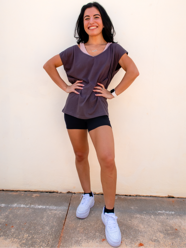 Young lady modeling a boxy, off-the-shoulder cotton/polyester dark grey t-shirt with a wide v-neck.