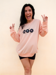 peach crewneck sweatshirt with 3 records that have music notes surrounding them printed on the front, and a colorful disco ball with the phrase "do a little happy dance" printed on the back
