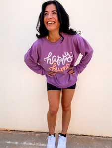 Young lady modeling a purple lightweight, crewneck sweatshirt with a hand-lettered script design saying "happy human" on the front in white and peach.