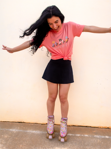 Pink graphic t-shirt with 3 pairs of colorful rollerskates and the phrase "let's go girls" printed underneath