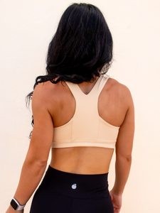 Young lady modeling a cream yellow colored sports bra with medium to high support and a unique racerback cut.