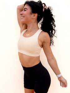 Young lady modeling a cream yellow colored sports bra with medium to high support and a unique racerback cut.