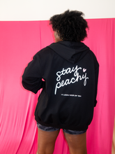 Load image into Gallery viewer, Oversized black zip up hoodie with Stay Peachy on the back with white and pink details
