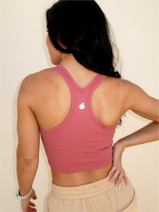 Young lady modeling a pink cropped racerback spandex tank with a built-in sports bra.