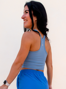 Young lady modeling a sky blue cropped racerback spandex tank with a built-in sports bra.
