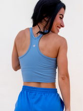 Load image into Gallery viewer, Young lady modeling a sky blue cropped racerback spandex tank with a built-in sports bra.
