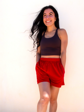 Load image into Gallery viewer, Young lady modeling comfortable red Sweatshorts in a lightweight material.
