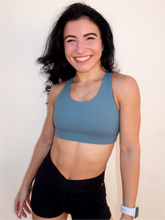 Load image into Gallery viewer, Stone green colored strappy sports bra with an open back and standard neckline that provides medium support.
