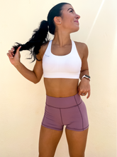 Load image into Gallery viewer, Young lady modeling Peachy Pia Peachy Shorts. Peachy Shorts are high-waisted in color lilac purple with a 75% nylon, 25% spandex blend. Extra stretchy fabric provides extra comfort while still providing a more fitted appearance.
