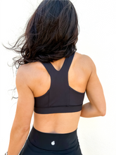 Load image into Gallery viewer, Lady modeling unique style black racerback sports bra.
