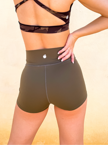 Young lady modeling Peachy Pia Peachy Shorts. Peachy Shorts are high-waisted in color olive green with a 75% nylon, 25% spandex blend. Extra stretchy fabric provides extra comfort while still providing a more fitted appearance.