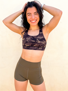 Young lady modeling Peachy Pia Peachy Shorts. Peachy Shorts are high-waisted in color olive green with a 75% nylon, 25% spandex blend. Extra stretchy fabric provides extra comfort while still providing a more fitted appearance.