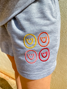 Grey, lightweight sweatshorts with multicolored smiley faces embroidered.