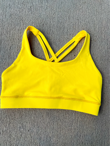 Young lady modeling Peachy Pia Worldwide Sports Bra. Sports bra is in color yellow with an 87% nylon, 13% spandex blend. Material is thick but flexible made to provide support and comfort.